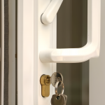 Close-up of a white door handle with a key and lock mechanism.