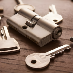 Close-up of a key and lock set with multiple keys placed on a wooden surface.